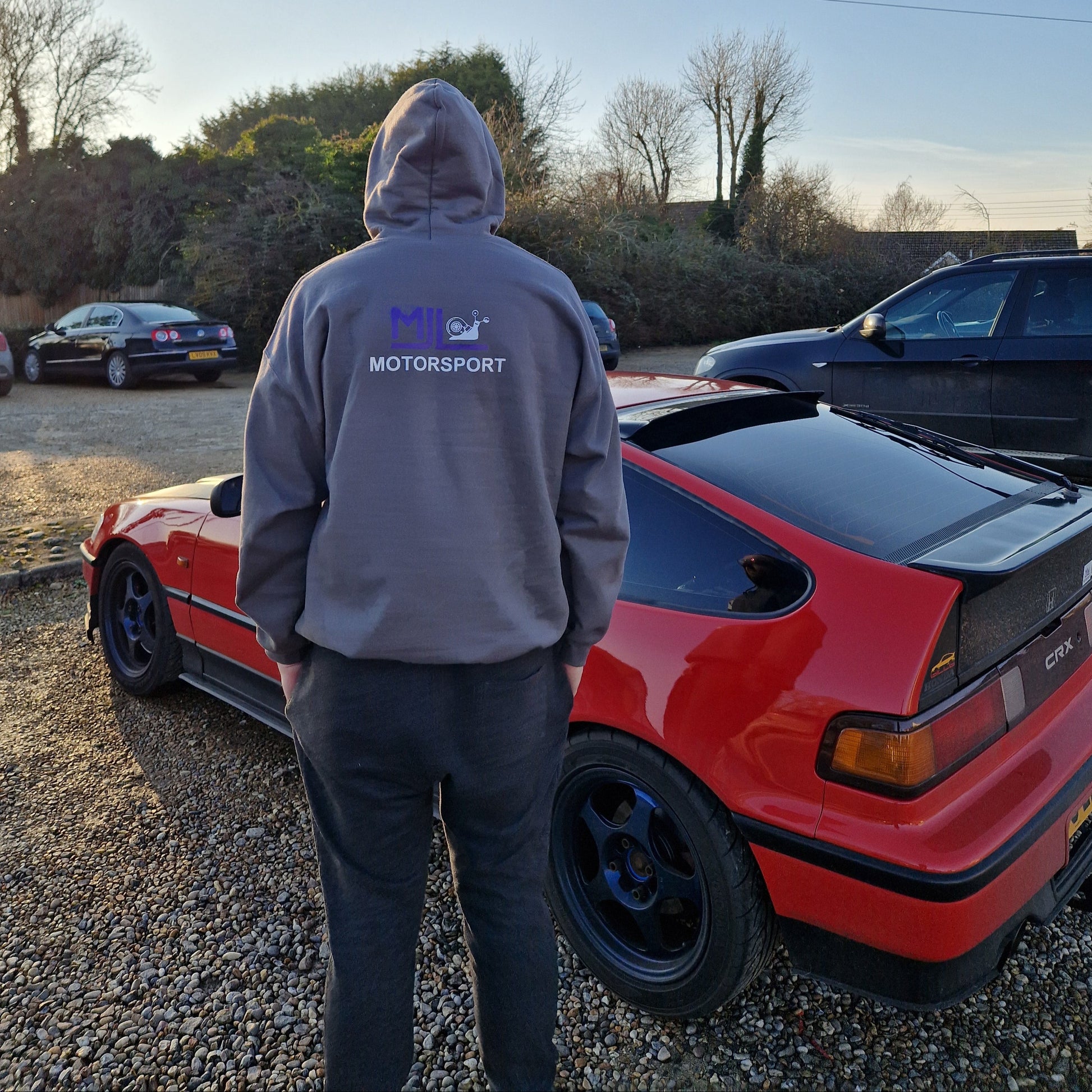 A person wearing  hoodie featuring MJL Motorsport logo