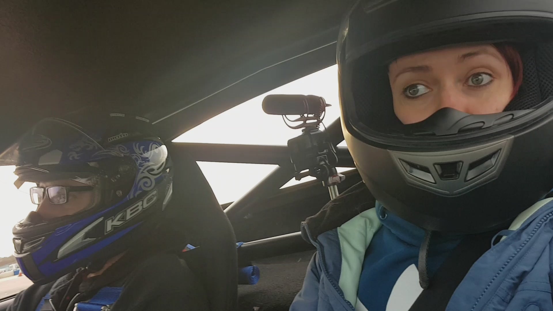 Load video: The driver is drifting the vehicle, the passenger is filming, both wearing helmets. The passenger has huge eyes and looks very scared.