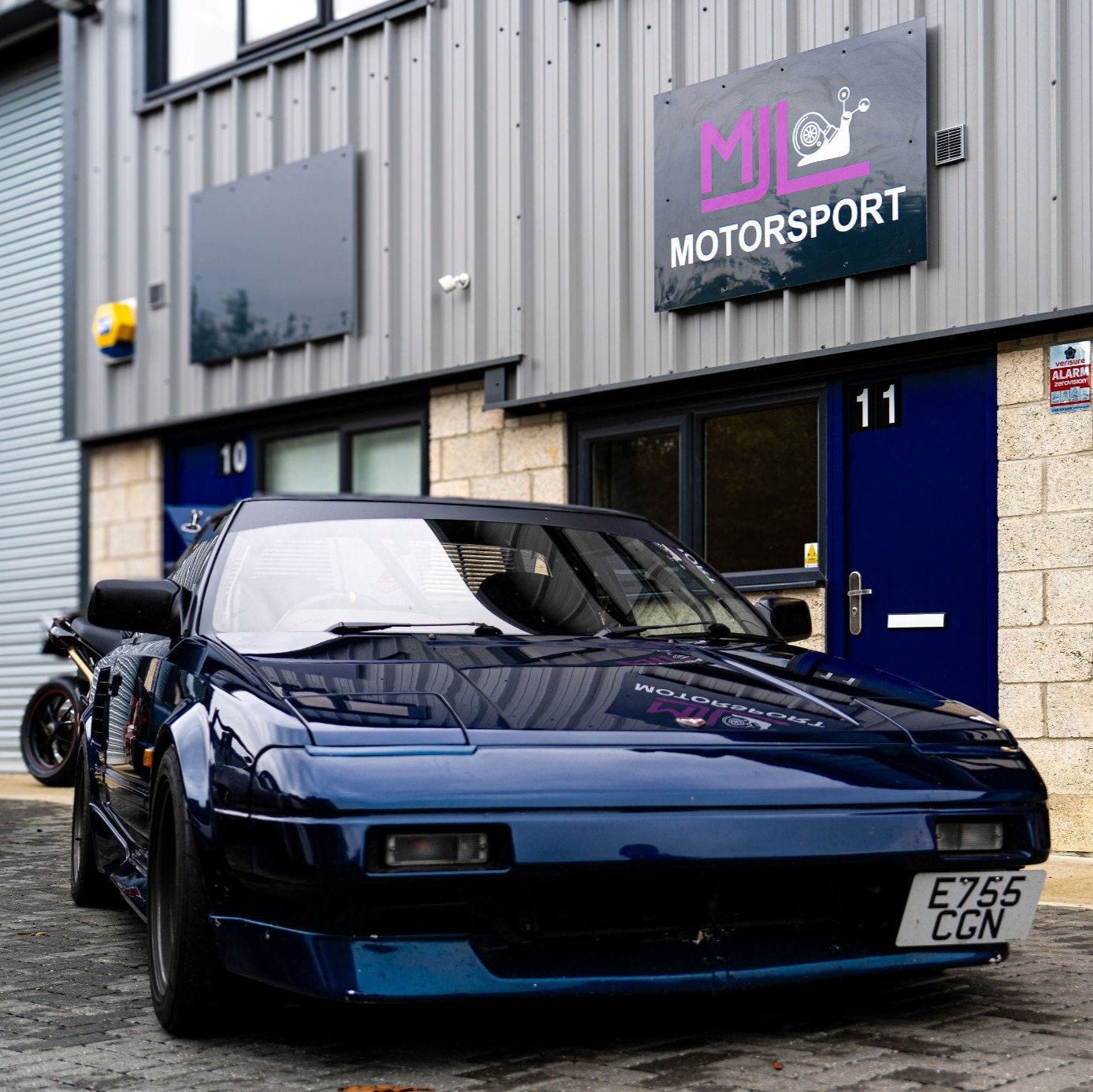 Blue mk1 Toyota MR2 parked next to MJL Motorsport workshop